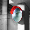 A convex car park safety mirror installed at a height on a concrete pillar.