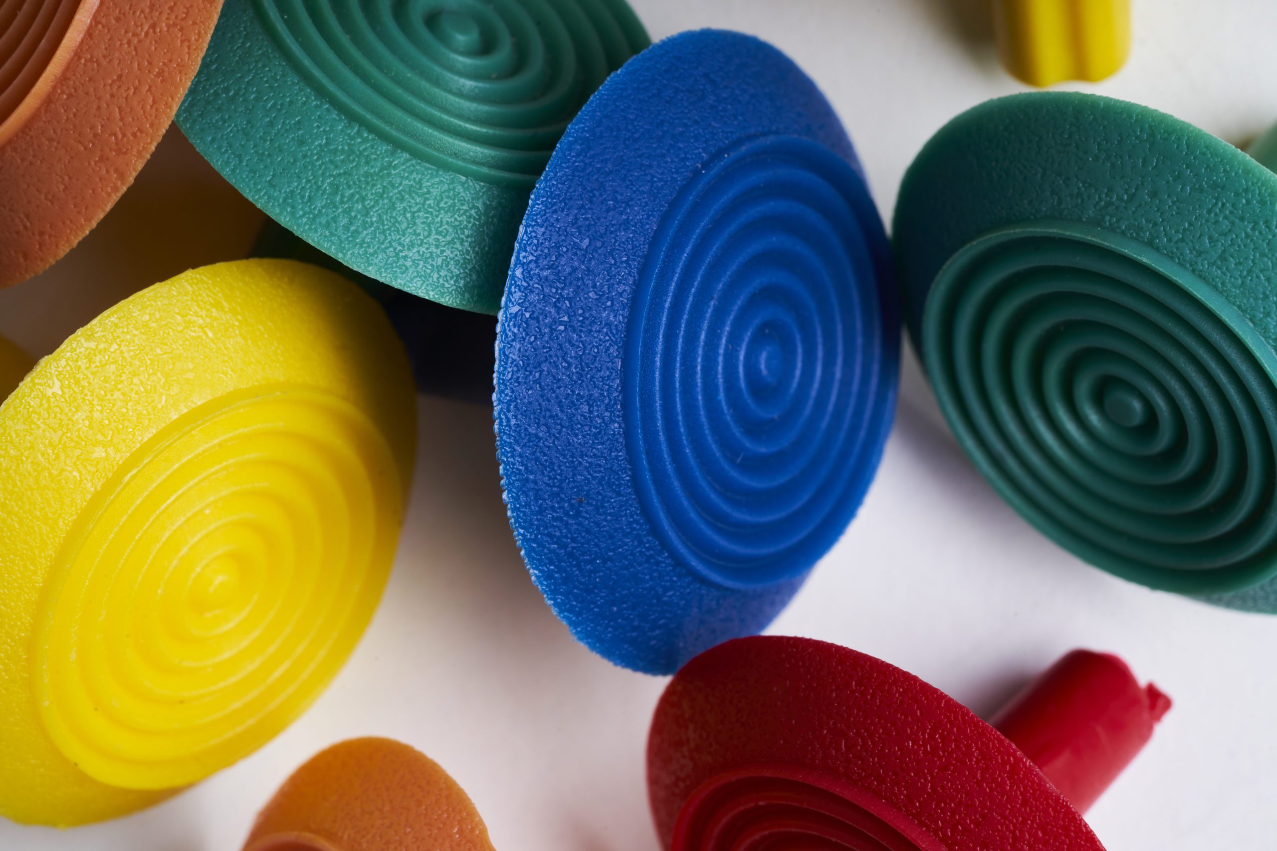 Polyurethane tactiles with a grooved ring top in yellow, blue and green colours.