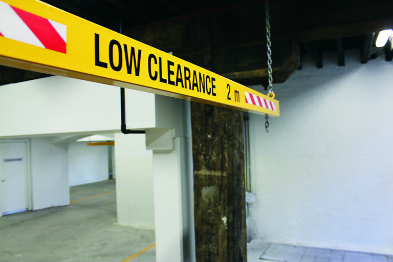 The side view of a yellow coloured height bar in an indoor car park.