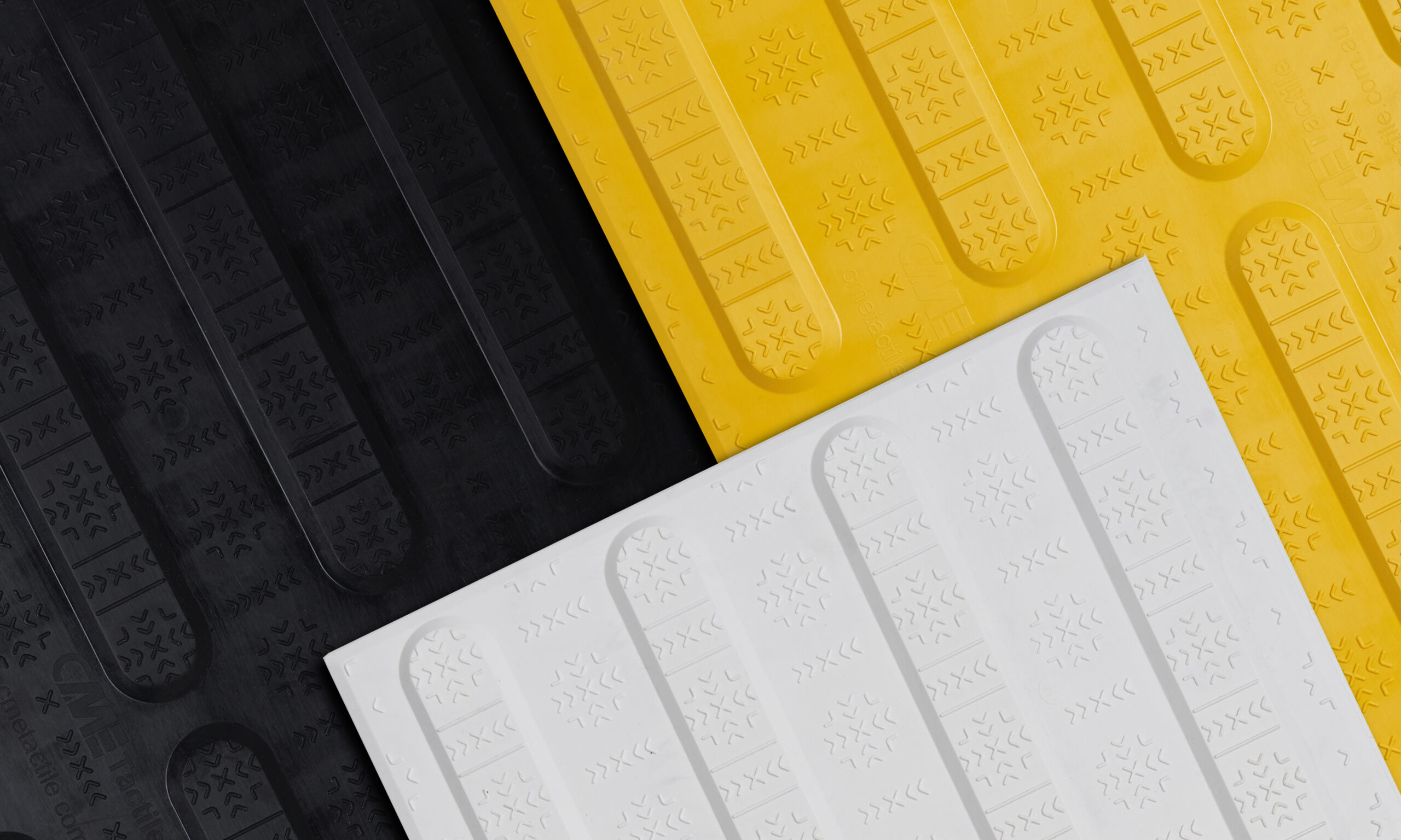 Zoomed in photo of yellow, black and white directional tactiles placed next to each other.