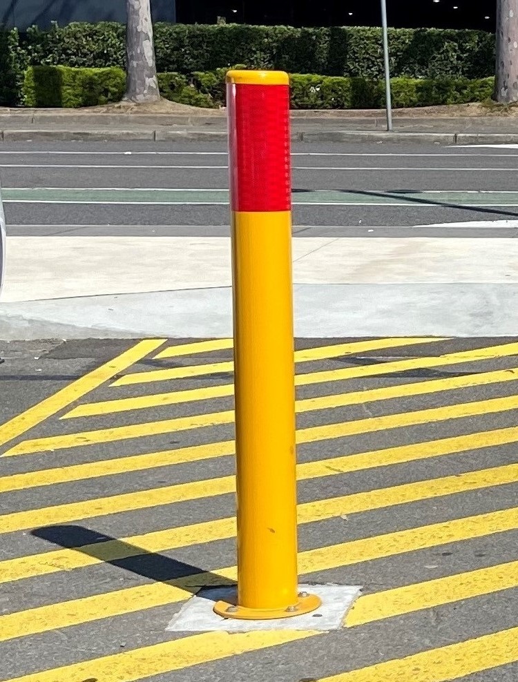 A disabled parking bollard installed in an outdoor car park to manage vehicle access.