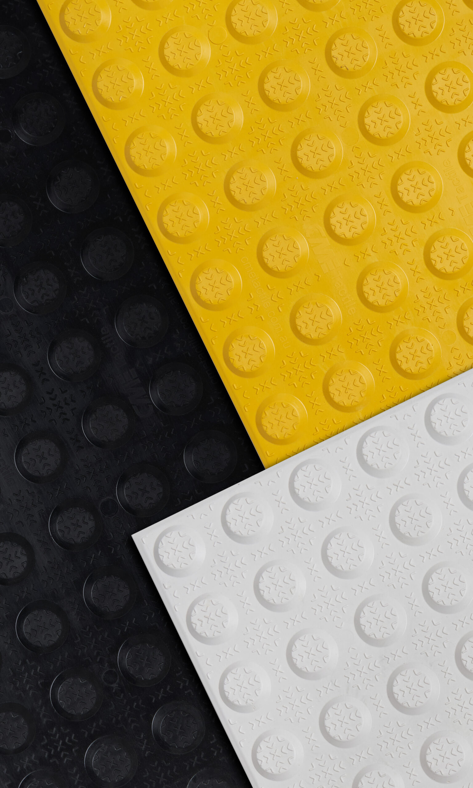 Close-up of fibreglass tactiles in black, yellow, and white. Each tile has a pattern of raised circles.