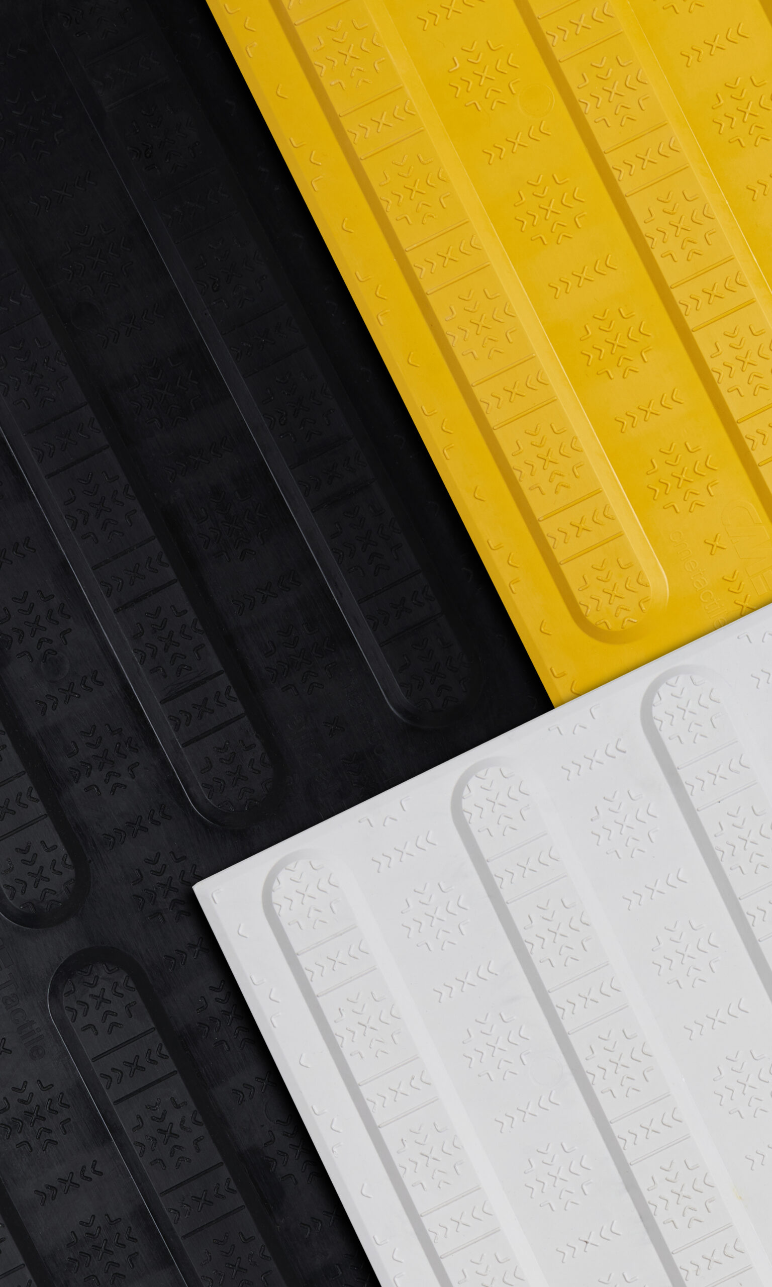 Close-up of directional tactiles in black, yellow, and white. Each tile has a textured top.