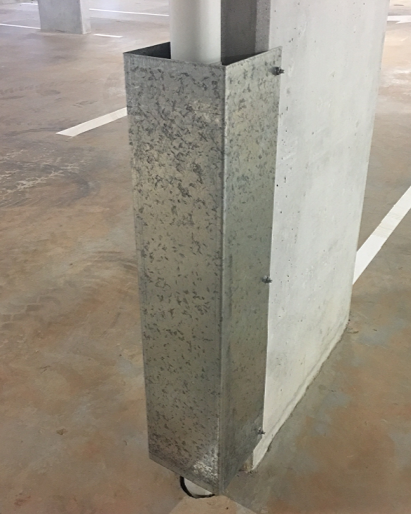 A pipe protector attached to a concrete column. The pipe guard has a white-coloured pipe running through it.